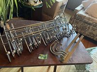 Photo of 7 chrome over door hangers laid on a table, clearly showing their metal structure and hooks.