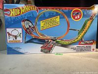 Overall front view of Hot Wheels box showing motorized loop and jump motorized raceway with 5 cars