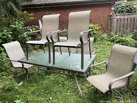 Patio table set with six chairs, two chairs placed on the glass table surface showing overall set and layout.