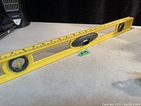 Full view of 24 inch yellow Stanley spirit level on a surface, showing the bubble vials and ruler markings.