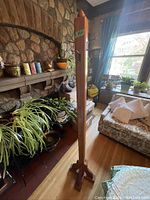 Front view of vintage pine coat tree standing adjacent to a stone fireplace and nearby couch in living room.