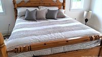 California King bed made with neutral color comforter set and 4 throw pillows visible