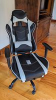 Front view of the black and gray PU leather ergonomic gaming chair showing the padded seat, headrest, lumbar cushion, and armrests.