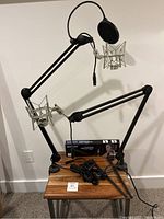 Full view of two microphone boom arms with shock mounts and pop filter attached on mic stand, cables coiled below