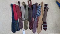 Overview of various neckties laid out showing different colors and patterns including blue, red, beige, purple, and olive with patterns such as stripes, dots, and geometric shapes.