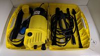 Top view of pressure washer main unit and accessories inside yellow molded plastic case