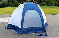 Blue and gray dome tent assembled outdoors, showing full exterior with yellow poles and access door.