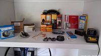 Full shelf view showing boxes of bike parts, tools and DeWalt battery pack