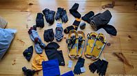 Photo showing full lot of winter apparel and small snowshoes laid out on wood surface: gloves (knit, fleece, leather), socks, hats and snowshoes