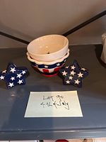 Photo of the 4th of July ceramic bowl with star-shaped salt and pepper shakers placed on a shelf with a label indicating the lot number and 4th of July theme