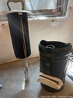Photo of a Burton golf bag with black and white details next to a silver pole with a black fabric cover, part of the pick-up machine.