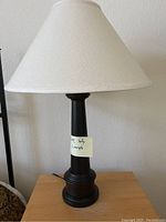 Left front view of one table lamp showing the black base with ridges and white fabric shade