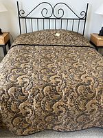 Queen bed with wrought iron headboard, paisley patterned bedspread, and bedside tables with lamps