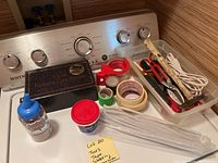 Overview photo showing screwdrivers, tape, scissors, cable, packing straps, small jar, and chair leather care system box arranged on counter
