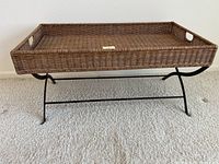 Side view of the wicker coffee table showing the tray top and wrought iron legs.