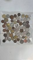 Top-down photo showing full assortment of approximately 60 assorted coins in various metals and sizes, displayed in rows inside a plastic bag.