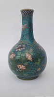 Front view of bottle-shaped vase showing neck and bulbous body with turquoise enamel and floral wire inlay