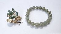 Photo showing jade bead bracelet and gold-tone green jade brooch