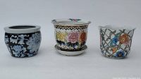 Three Chinese flower pots in different floral patterns and designs, displayed side by side.