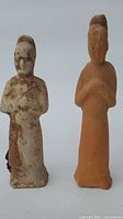 Two standing Chinese terracotta figurines shown from front, worn and eroded