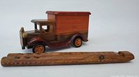 Wooden vintage truck with hinged roof compartment next to carved wooden flute showing overall size and details.