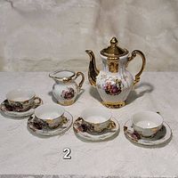 Full tea set displayed on white cloth background showing teapot, creamer, four cups and four saucers.
