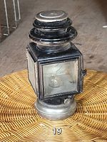Front view of antique black carriage lantern lamp showing glass panel and metal details