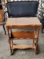Solid wood antique side table showing front with turned legs, scalloped edge on top, and lower shelf.
