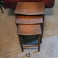 Stacked view of three nesting tables showing the tops and parts of legs.