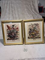 Two framed vintage Furber flower prints titled August and May, with colorful floral arrangements displayed against a cream backdrop, in gold frames.