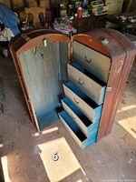 Opened travel wardrobe trunk showing 5 blue fabric-lined drawers with brass handles on one side and an empty hanging compartment on the other. Interior blue lining shows some wear.