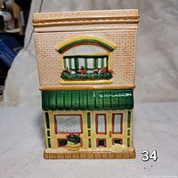 Front view of the ceramic bakery cookie jar showing the green awning, bakery sign, double doors, and upper window with flower box.