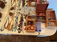 Top view of assorted necklaces, bracelets, pendants, and small bags with broken beads spread out on table