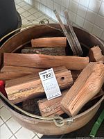 Overhead view of copper bucket filled with firewood and inventory tag
