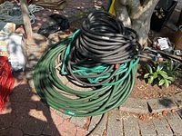 Photo of two coiled hoses—one green garden hose and one thick black rubber hose