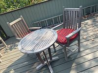 Table and two chairs on deck from front, one chair with red and white striped cushion