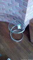 Round glass accent table showing coiled tubular metal base and clear glass top