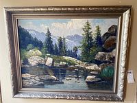 Full view of original framed landscape oil painting with mountains, trees, rocks, and water.