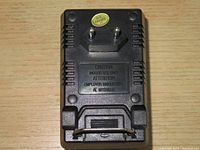 Back side of black voltage converter showing two-prong plug and warning label