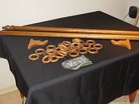 Maple wood drapery rod, two wood brackets, and 28 matching wood rings displayed on black cloth.