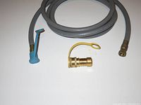 Photo of grey flexible natural gas hose coiled, showing brass quick connect fitting, blue shut-off valve, and separate brass adapter with yellow plastic loop.