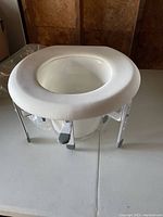 Raised toilet seat with adjustable legs on table