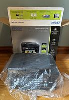 Boxed Epson WorkForce WF-2540 printer with original packaging and wrapped in plastic, showing front and top sides.