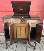 Victrola phonograph wooden cabinet with open lid and front doors showcasing internal compartments and speaker grille.