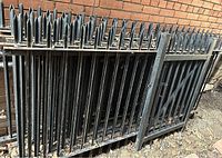Stacked black wrought iron panels with pointed picket tops against a brick wall.