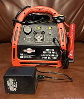 Front view of MotoMaster battery booster pack showing 700 peak amps, 350 crank assist amps, control switches, LED lights, USB port, and jump starter clamps.