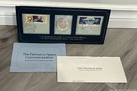 Full view of the display case containing the silver coin centered between two commemorative Apollo Soyuz space mission stamps. Included are two informational inserts from The Franklin Mint.