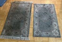 Two vintage handmade Persian carpets side by side on wooden floor, multi-coloured with floral and geometric patterns and fringed edges.