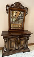 Full view showing the cabinet and mounted mirror on top with detailed carving at the top and sides.