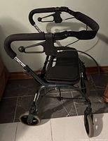 Side and rear angled view showing the walker frame, handlebars with brake levers, wheels, seat and backrest.